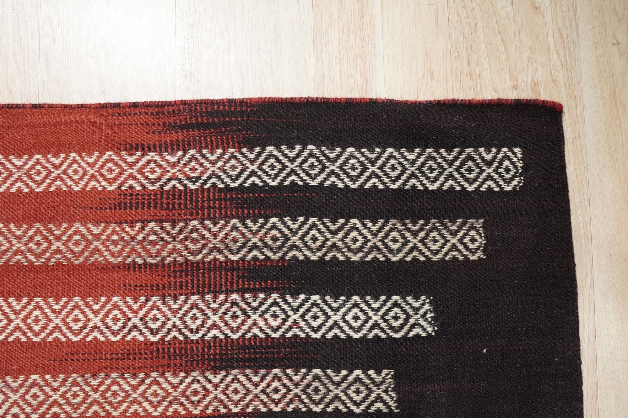Dazzling Sleek Red Flatweave Wool Rug anchors a contemporary living space. The vibrant red flatweave wool rug, with subtle textural variations, complements a modern sofa and natural wood furniture, creating a warm and inviting atmosphere.
