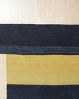 Celia Nadia Multicolor Flatweave Wool Rug, a vibrant tapestry of woven hues, lies on a polished hardwood floor; warm tones of red, orange, and yellow intermingle with cool blues and greens in a captivating flatweave design, creating a visually stunning focal point.