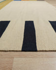 Celia Nadia Multicolor Flatweave Wool Rug displayed on a light wood floor, its vibrant hues and geometric pattern bringing warmth and modern style to the room.