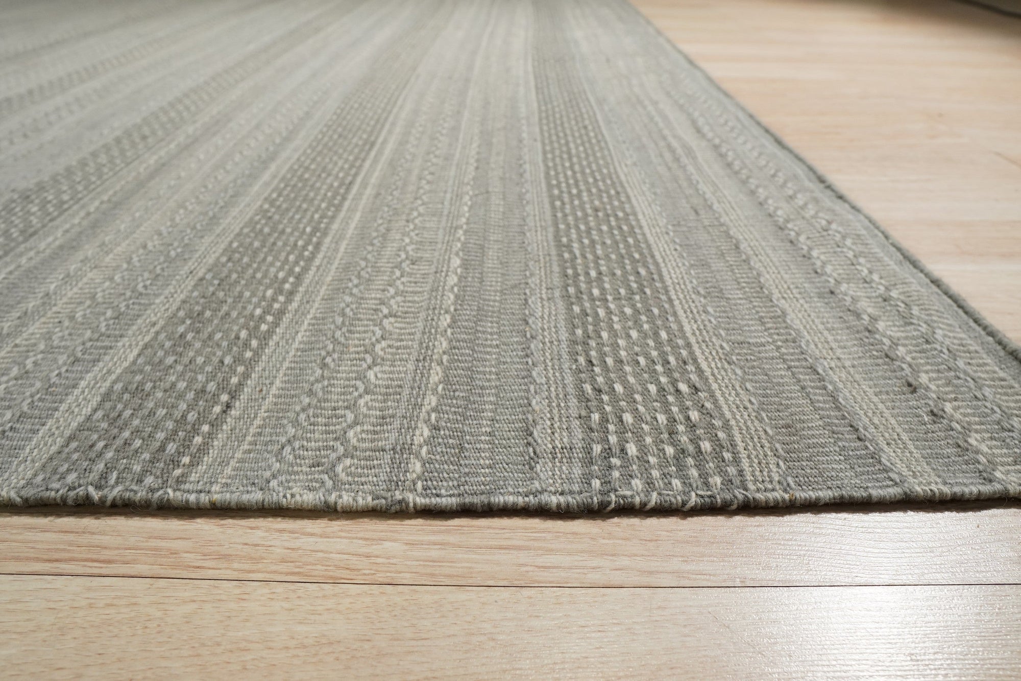 Captivating Talia Gray Handmade Wool Rug, a soft gray wool rug with a subtle, textural design, displayed in a bright living room setting.