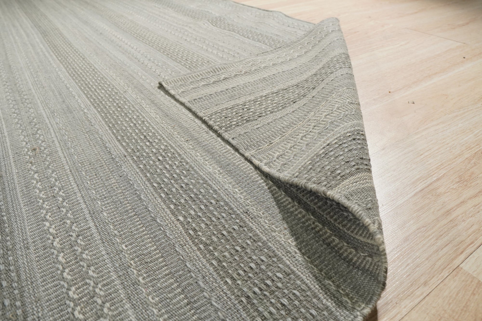 Captivating Talia Gray Handmade Wool Rug, soft gray and ivory tones blend in a living room setting, its subtle pattern complementing a modern sofa and minimalist decor.