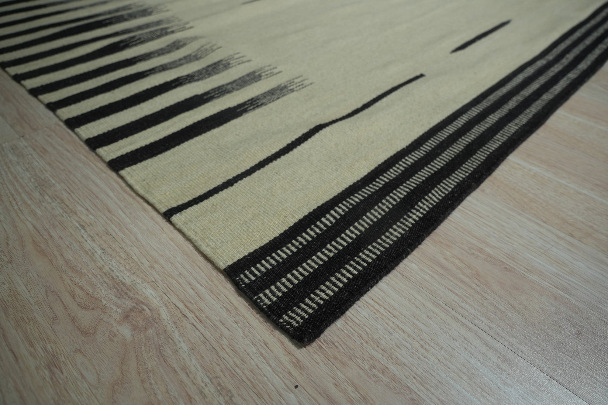 Sloane Majestic Gray Flatweave Wool Rug, with its subtle patterns and cool gray tones, anchors a bright, modern living room featuring light wood furniture and pops of yellow accents.