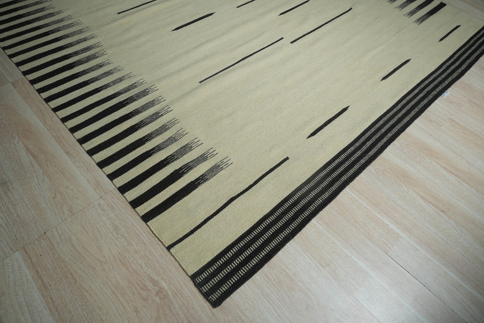Sloane Majestic Gray Flatweave Wool Rug, seen in a living room setting, features a subtle geometric pattern in shades of gray and off-white, lending a touch of modern elegance to the space.