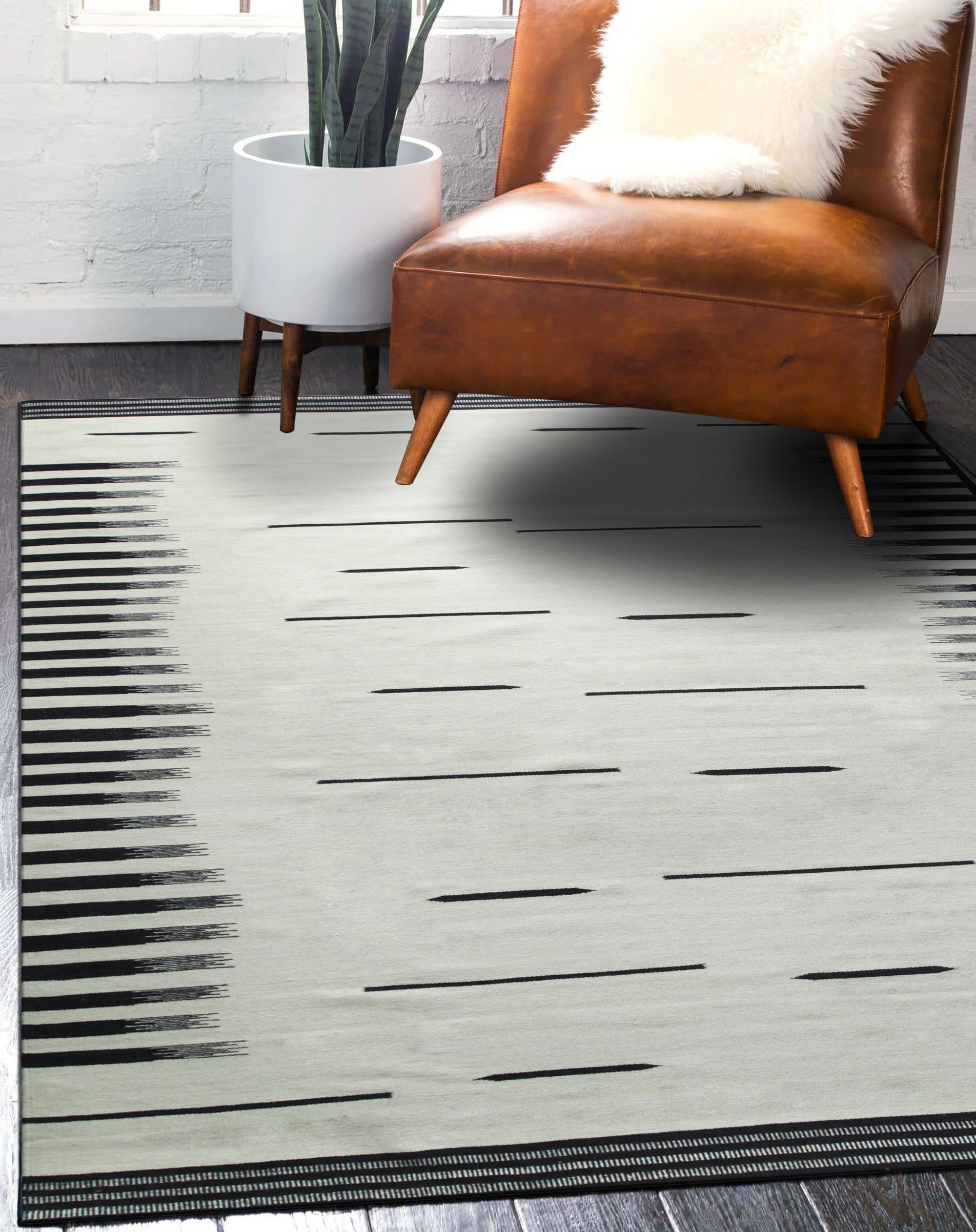 Sloane Majestic Gray Flatweave Wool Rug, a cool-toned flatweave brings subtle texture to a modern living space, grounding a light wood coffee table and patterned armchair with its calming gray hues.