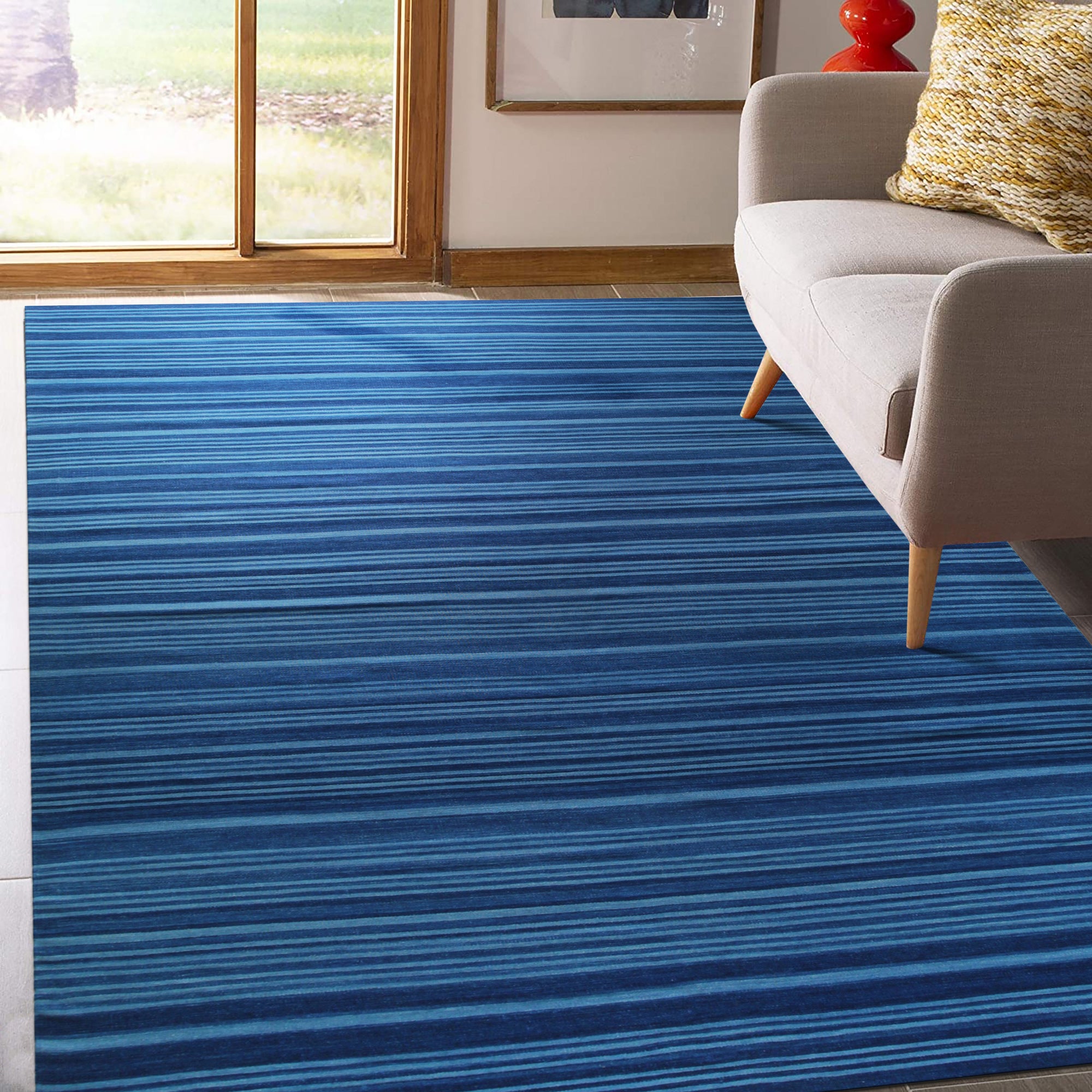 Para Penelope Blue Flatweave Wool Rug, anchoring a bright living space with a textured geometric pattern in shades of blue and cream, its flatweave construction providing a grounding softness under a modern coffee table and plush velvet seating.
