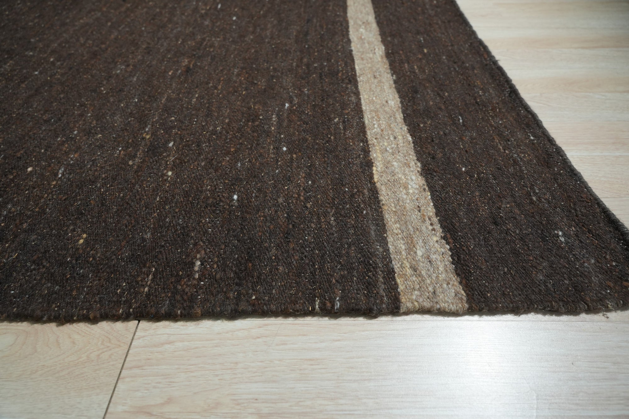 Violet Artistic Brown Flatweave Wool Rug, a blend of earthy browns and violet hues in a subtly textured wool flatweave, displayed in a bright, modern living room setting.