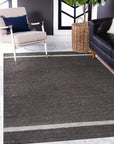 Violet Artistic Brown Flatweave Wool Rug, showcasing a textured, layered effect in shades of brown and violet, laid on a light wood floor; a modern and minimalist design.
