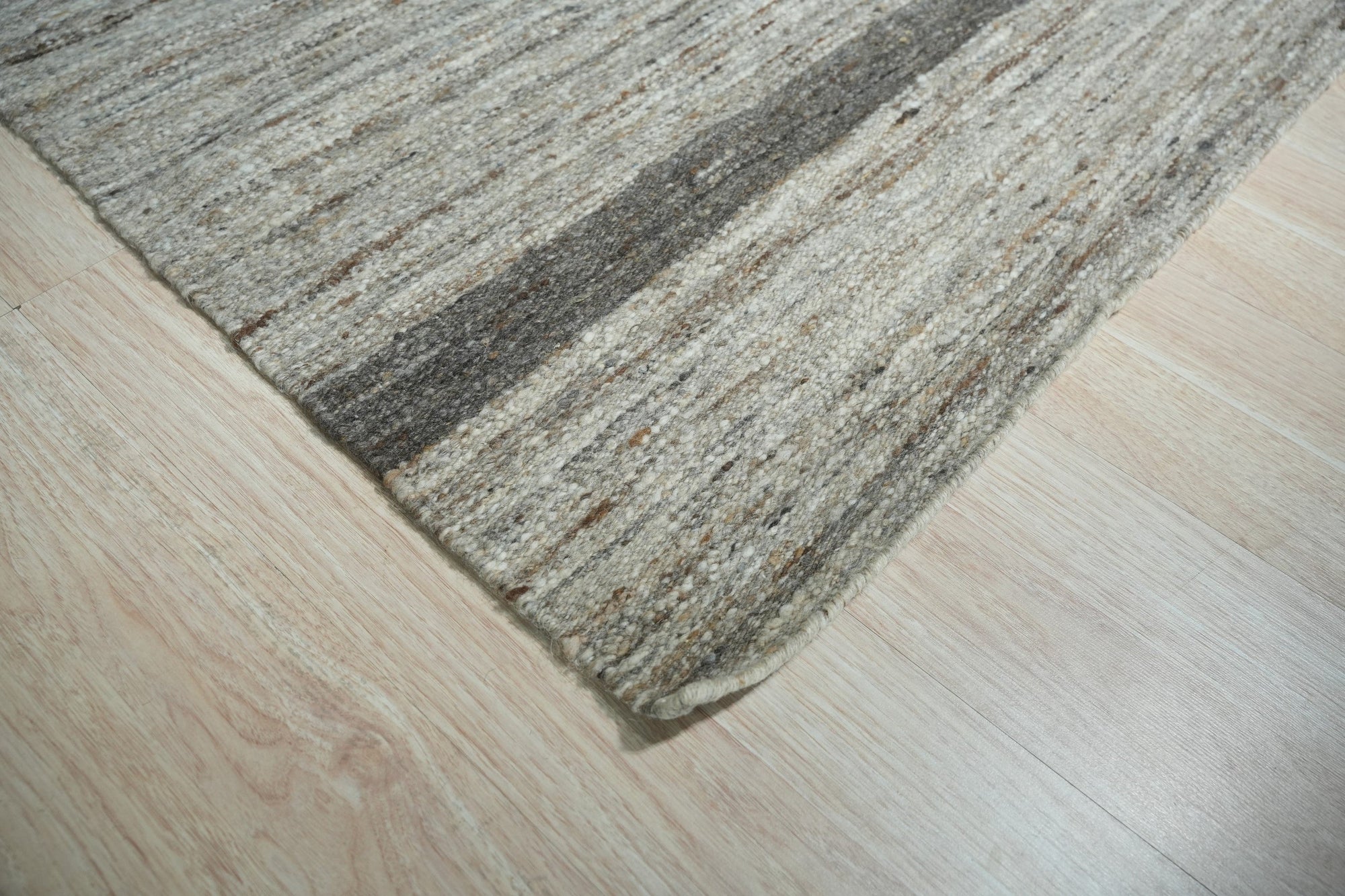 Lila Violet Light Gray Flatweave Wool Rug, its subtle violet and light gray tones blending in a soft flatweave texture, displayed within a brightly lit interior.