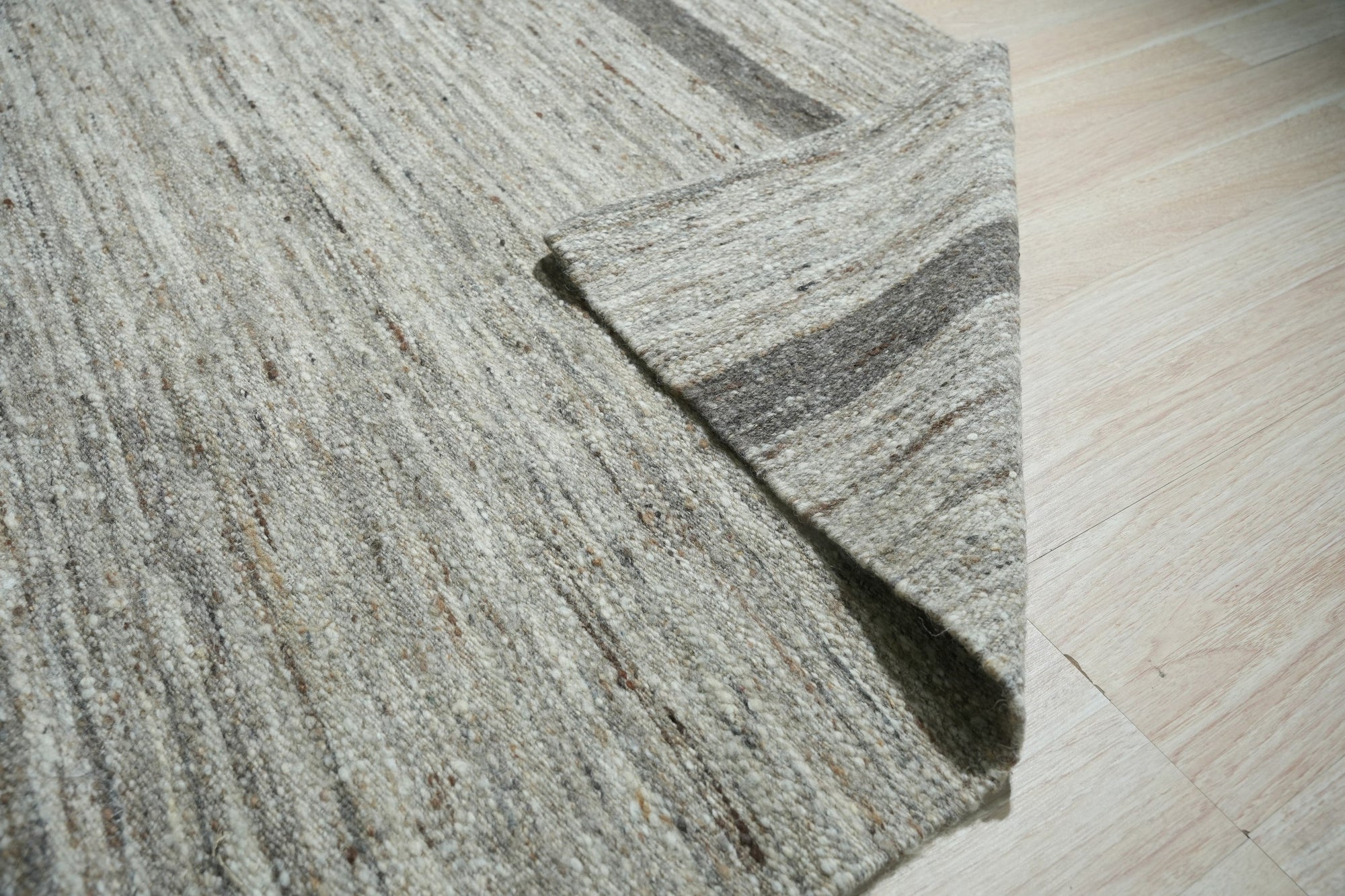 Lila Violet Light Gray Flatweave Wool Rug, soft hues blending in a contemporary living space. Flatweave construction highlights subtle shifts of violet, light gray, and cream wool, grounded by natural hardwood flooring and bathed in warm light.