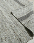 Lila Violet Light Gray Flatweave Wool Rug, soft hues blending in a contemporary living space. Flatweave construction highlights subtle shifts of violet, light gray, and cream wool, grounded by natural hardwood flooring and bathed in warm light.