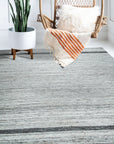 Lila Violet Light Gray Flatweave Wool Rug in a bright, minimalist living room setting; the rug's flatweave construction and subtle violet and light gray tones complement the modern decor.