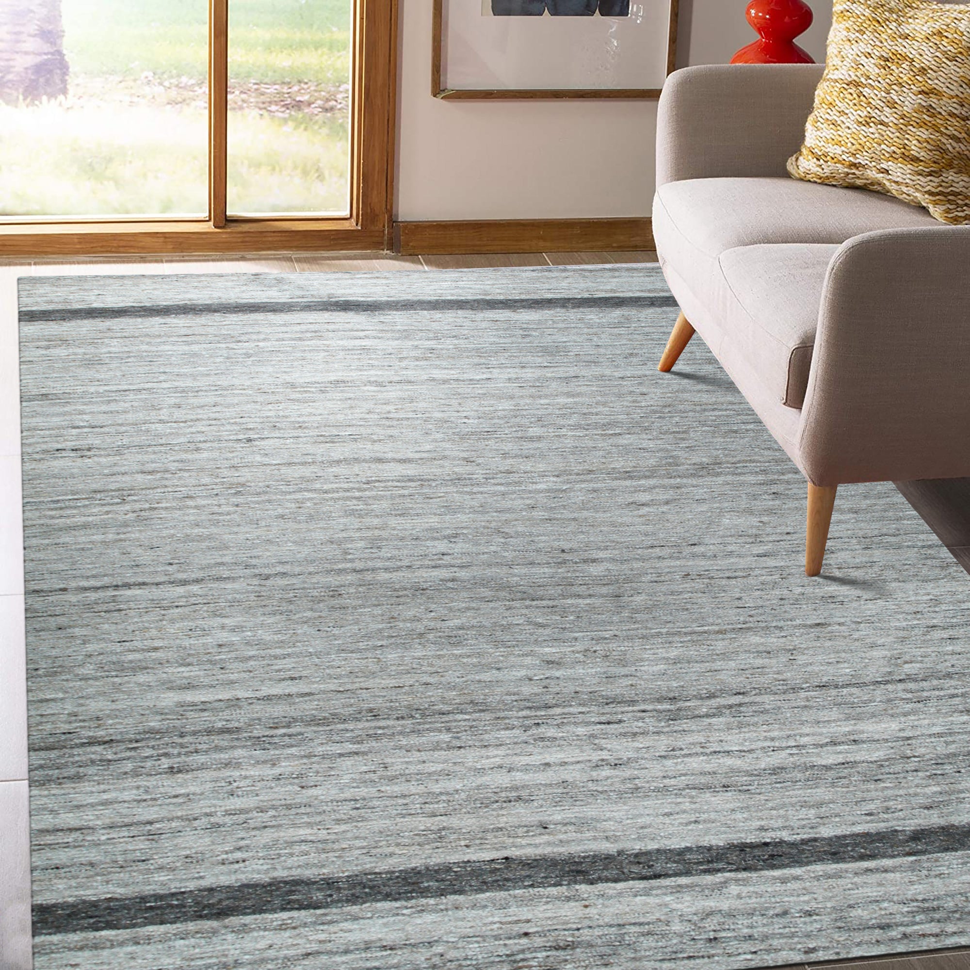 Lila Violet Light Gray Flatweave Wool Rug graces a bright living room, its subtle violet and light gray hues grounding the space. Woven wool flatweave texture visible, complementing modern furniture.