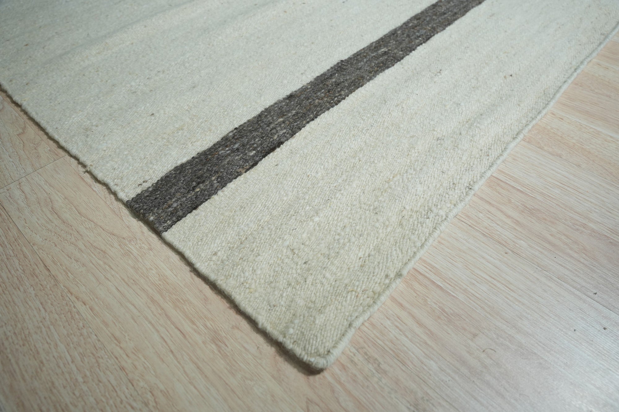 Artisan Nadia Ivory Flatweave Wool Rug, its subtle geometric pattern complementing a modern living room setting with light hardwood floors and neutral furnishings.