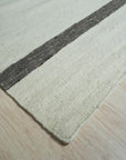 Artisan Nadia Ivory Flatweave Wool Rug, its subtle geometric pattern complementing a modern living room setting with light hardwood floors and neutral furnishings.