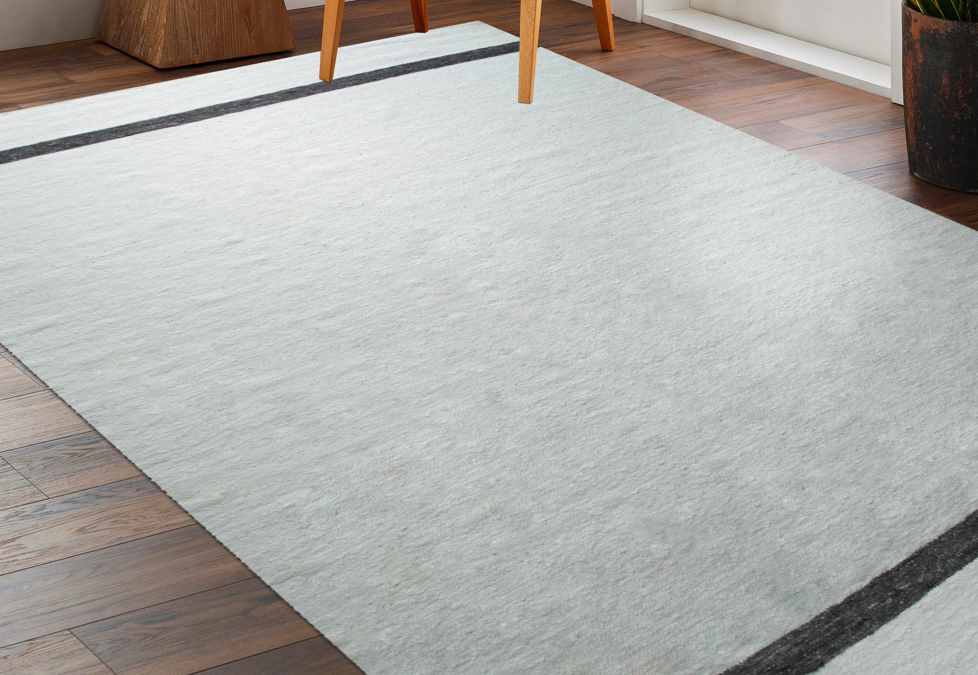 Artisan Nadia Ivory Flatweave Wool Rug anchors a bright, airy living room, its subtle texture complementing the modern décor. Natural light highlights the rug's creamy ivory hues and flatweave construction.