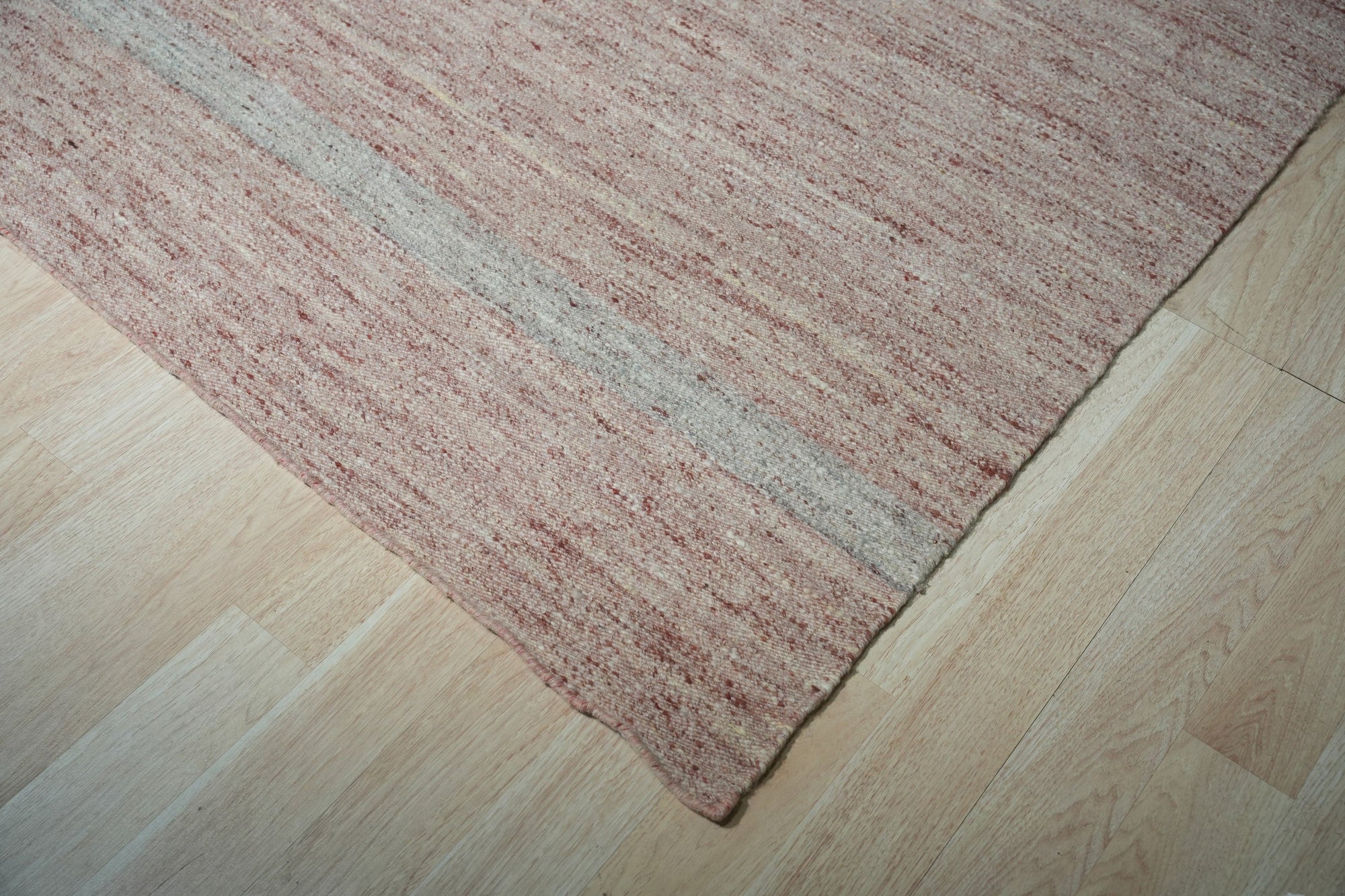 Rhea Selene Pink Flatweave Wool Rug, its delicate blush tones and intricate geometric design adding warmth and texture to a modern living room.