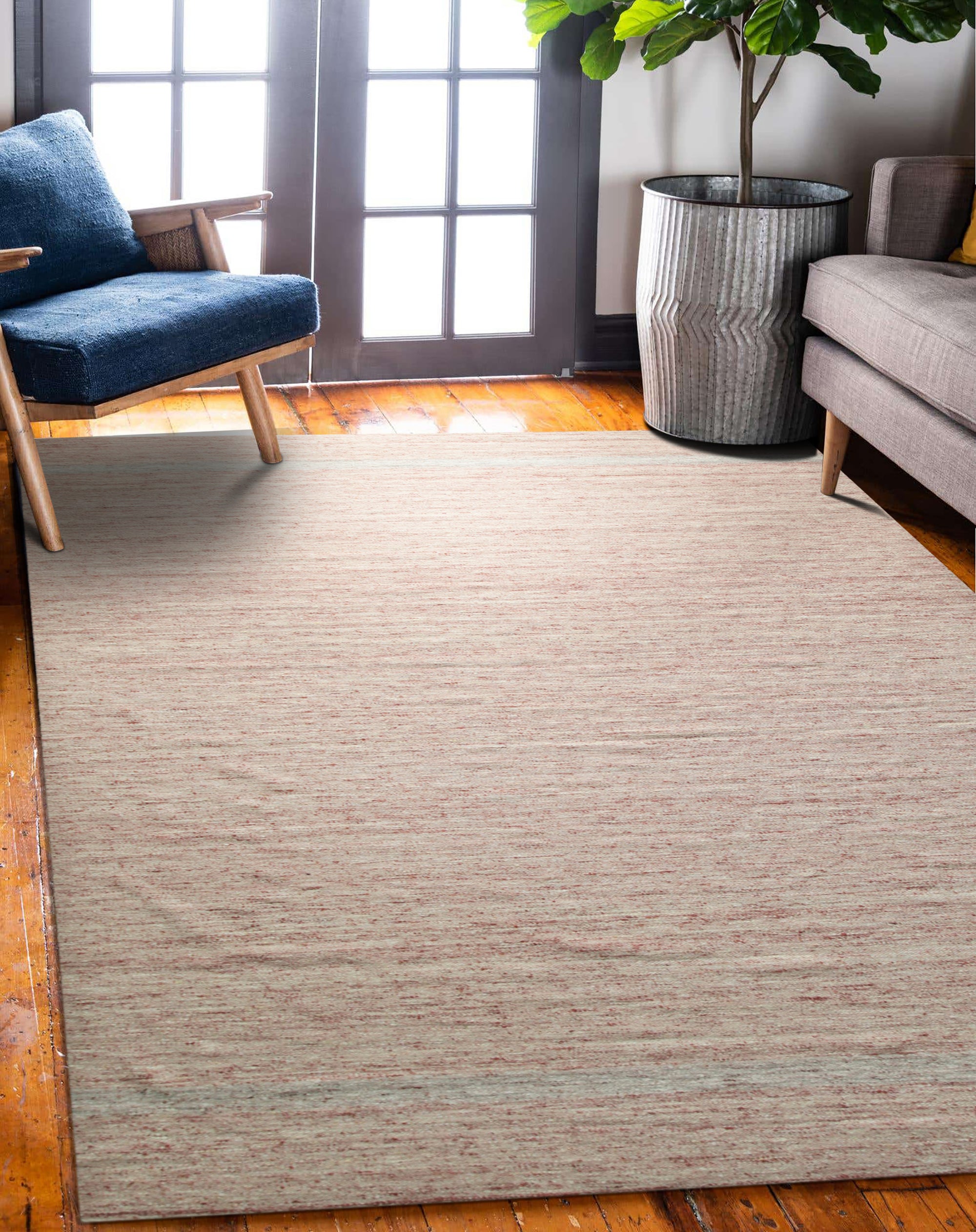 Rhea Selene Pink Flatweave Wool Rug, a soft pink and cream wool rug with a geometric diamond pattern, anchoring a bright, modern living room with a white sofa and gold accents.