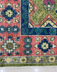 High-pile rug corner showing vivid geometric designs in pink, blue, lime green, and teal on white tile.