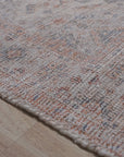 Refined Fiona Blue Handmade Wool Rug, seen with a blurred background, hints at its elegant blue tones and plush wool construction, suggesting a luxurious feel underfoot.