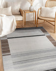 Classic Reversible Delicate Brown Flatweave Wool & Viscose Rug, seen in a warmly lit living room setting. Subtle pattern dances across its flatweave surface, blending seamlessly with the hardwood floor and neutral decor. The brown wool and viscose construction offers a sophisticated, textured feel.