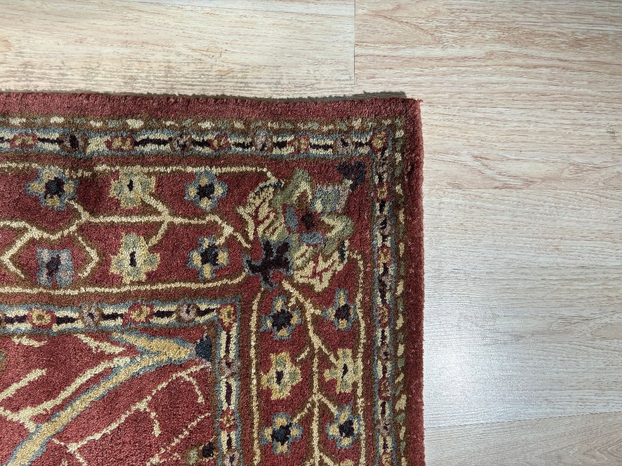 Lydia Vibrant Red Hand Tufted Wool Rug anchors a modern living room. Its vibrant red wool construction radiates warmth against a light wooden floor, surrounded by neutral furniture.