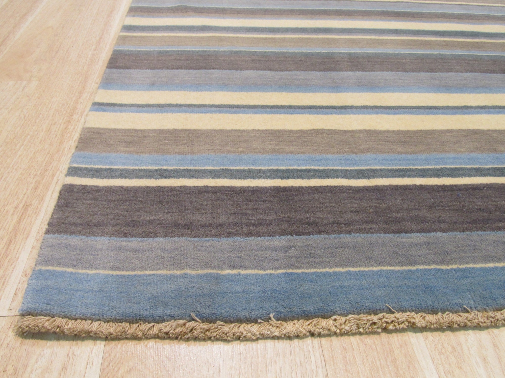 Lila Fiona Multicolor Handmade Wool Rug, displaying vibrant geometric patterns in blues, pinks, yellows, and creams, covering a hardwood floor and partially underneath a light wood coffee table.