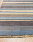 Lila Fiona Multicolor Handmade Wool Rug, displaying vibrant geometric patterns in blues, pinks, yellows, and creams, covering a hardwood floor and partially underneath a light wood coffee table.