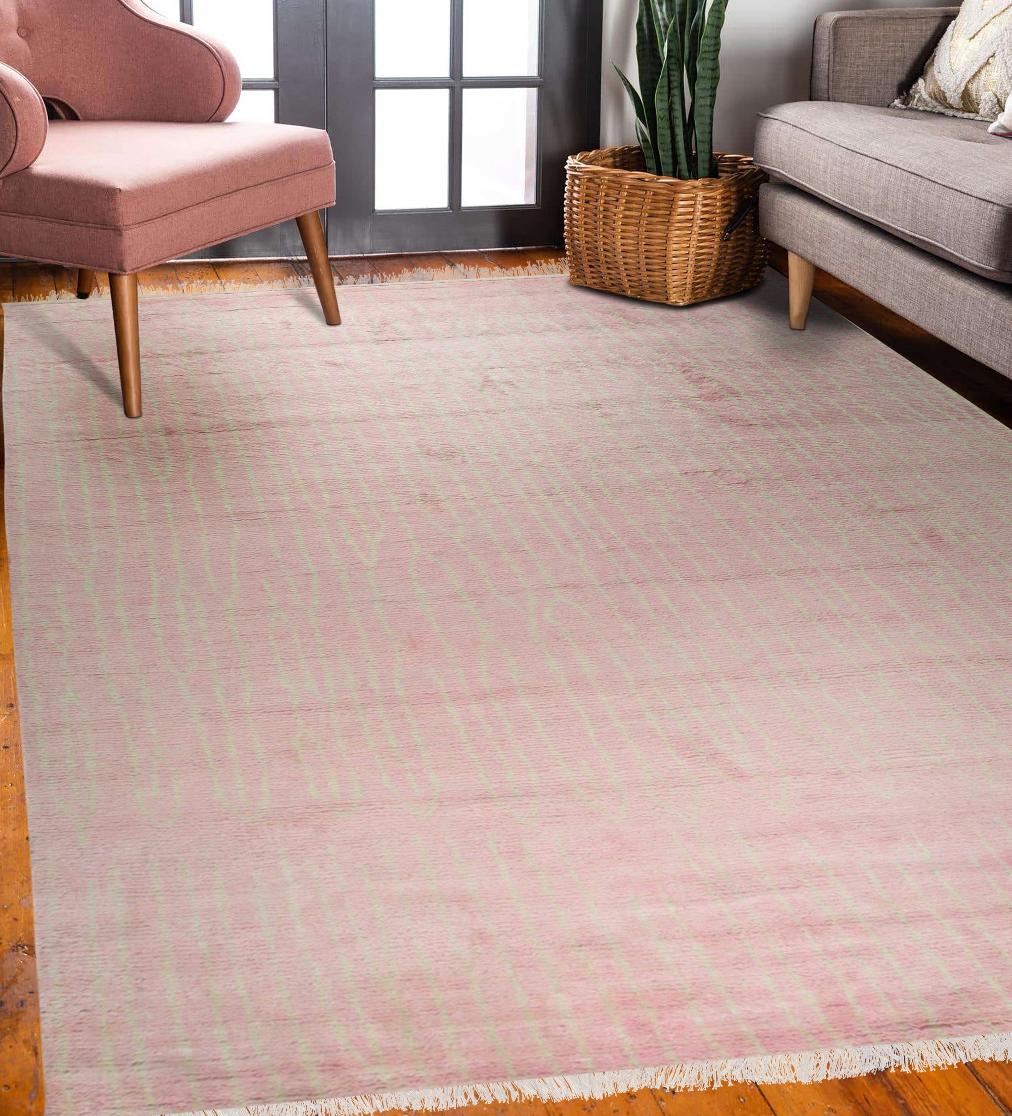 Rhea Moroccan Pink Hand Knotted Wool Rug, its delicate pink hues and intricate hand-knotted texture softening a light-filled living space with warm hardwood floors and modern furniture.