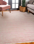 Rhea Moroccan Pink Hand Knotted Wool Rug, its delicate pink hues and intricate hand-knotted texture softening a light-filled living space with warm hardwood floors and modern furniture.