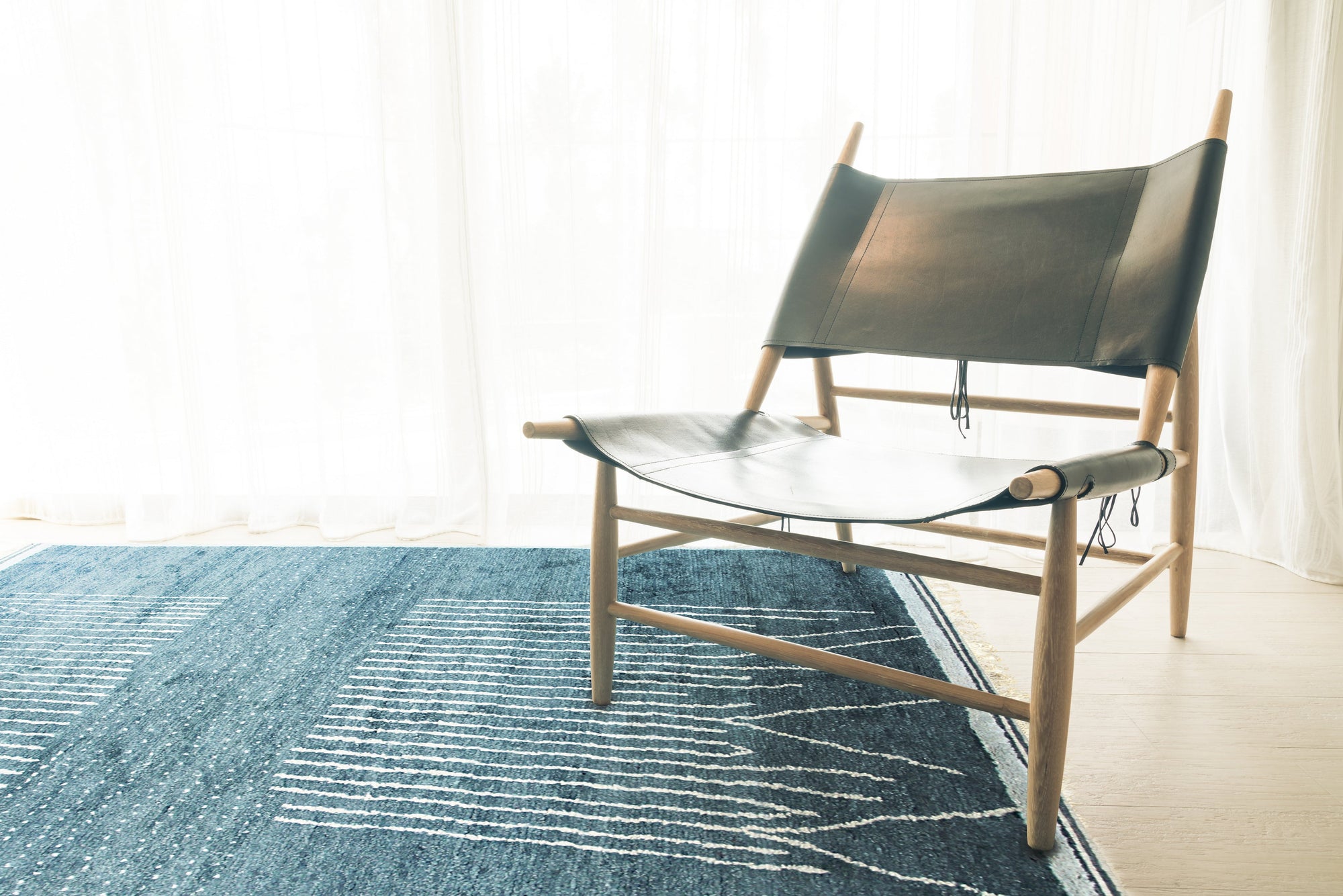 Freya Moroccan Green Hand Knotted Wool Rug, showcasing a geometric diamond pattern in shades of green and cream, rests on a light hardwood floor, adding warmth and texture to a modern living space.