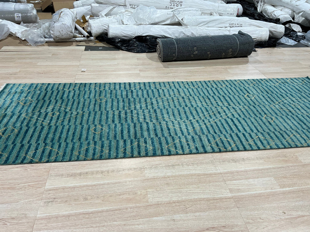 Exquisite Moroccan Handmade Wool Green Rug, its textured pile vibrant emerald and moss, lies centered in a sunlit room, intricate geometric patterns adding warmth and character to the hardwood floor.
