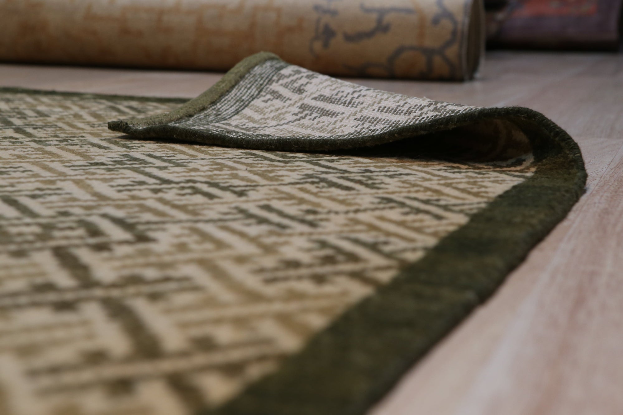 Sophisticated Nadia Black Hand Knotted Wool Rug featuring a subtle, intricate pattern, laid on a light hardwood floor with a hint of sunlight streaming in, highlighting the rug's depth and texture.