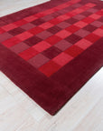 Para Opulent Red Hand Tufted Wool Rug, its deep red wool pile inviting touch, lies centered in a brightly lit space; its hand-tufted construction suggests luxurious comfort beneathfoot.