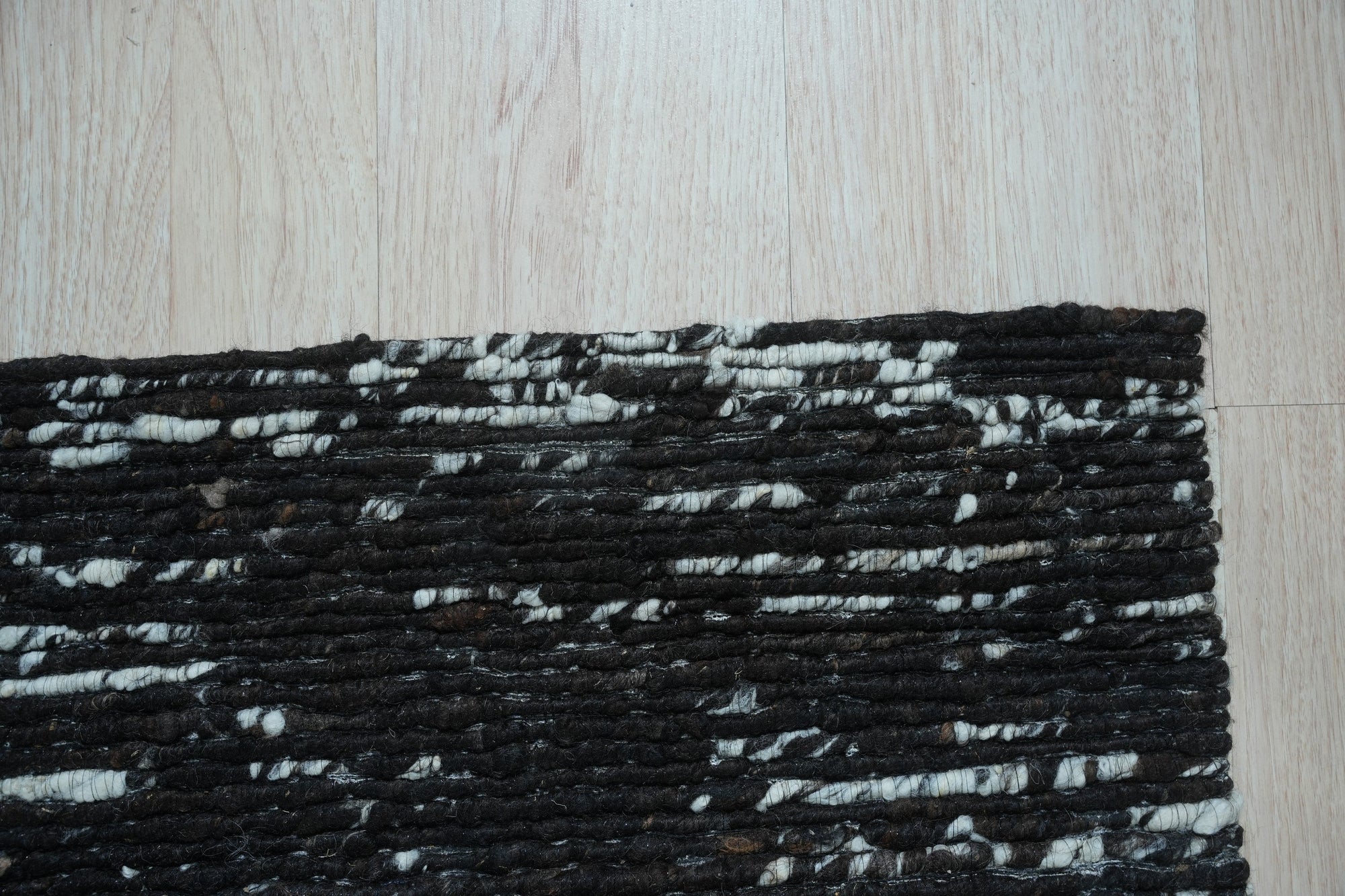 Fiona Rustic Black Flatweave Wool Rug, a black wool rug with a rustic design, seen in a room setting, displaying its texture and scale.