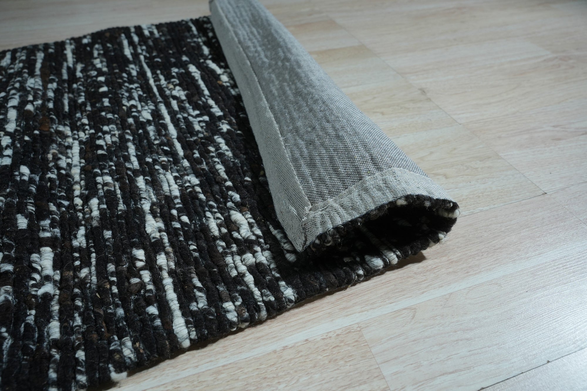 Fiona Rustic Black Flatweave Wool Rug, flatwoven in deep black wool, adds rustic texture to a light-filled room with minimalist decor.