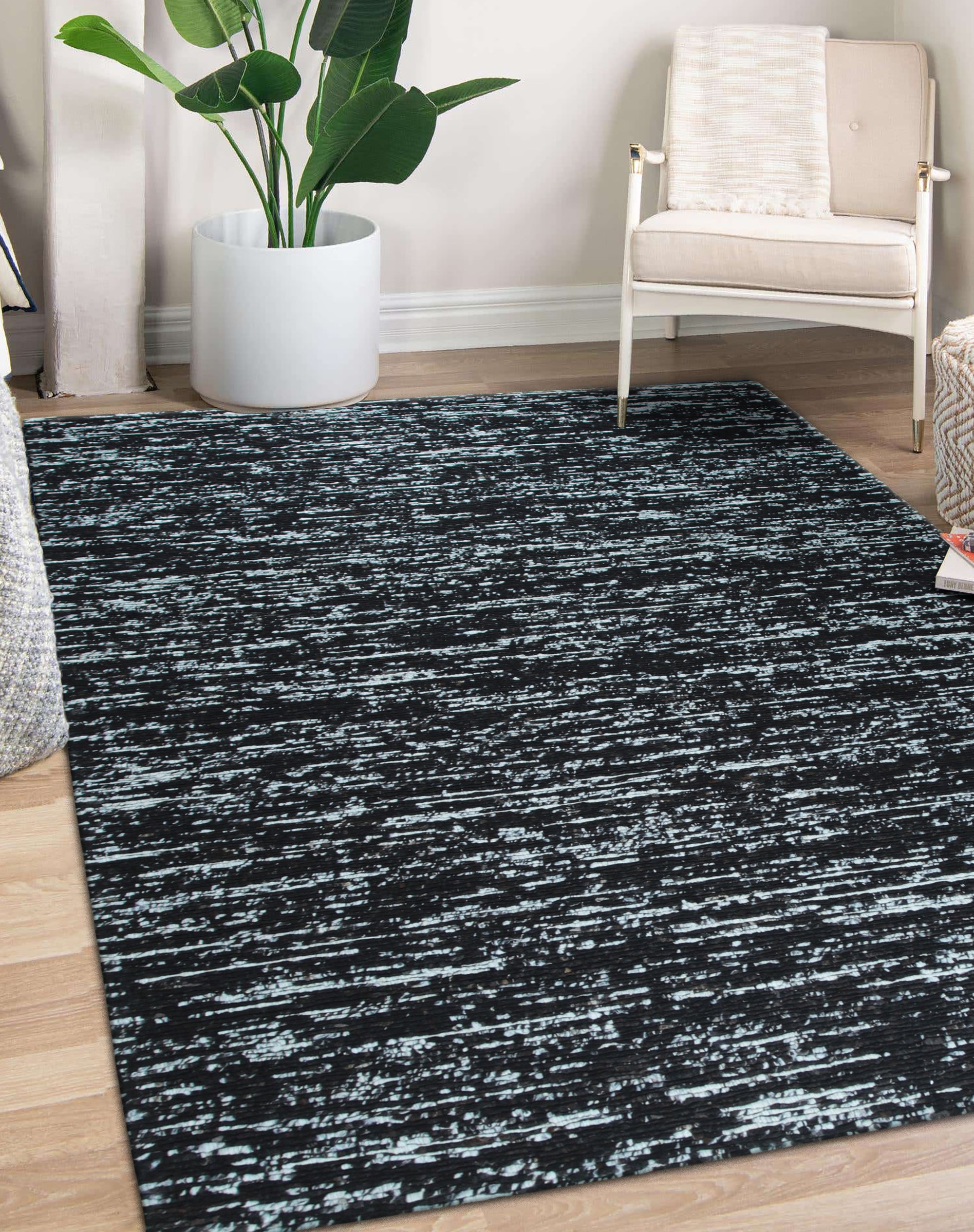 Fiona Rustic Black Flatweave Wool Rug, anchoring a modern living room with its textured, dark wool. Warm light highlights subtle variations in the flatweave construction.