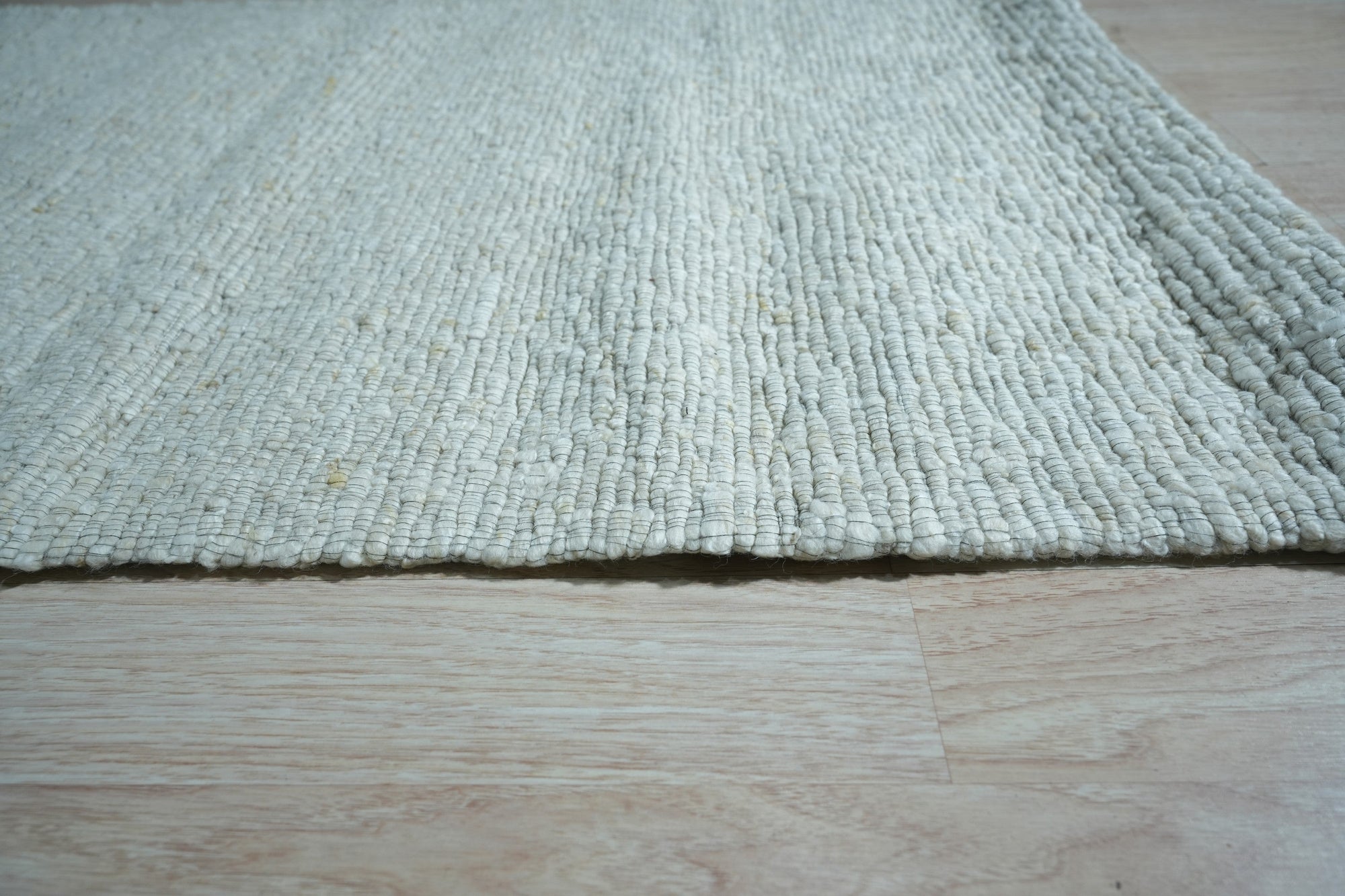 Fiona Rustic Ivory Flatweave Wool Rug, bringing understated elegance to a naturally lit living space. Woven wool and its creamy ivory tones soften the dark wood floor.