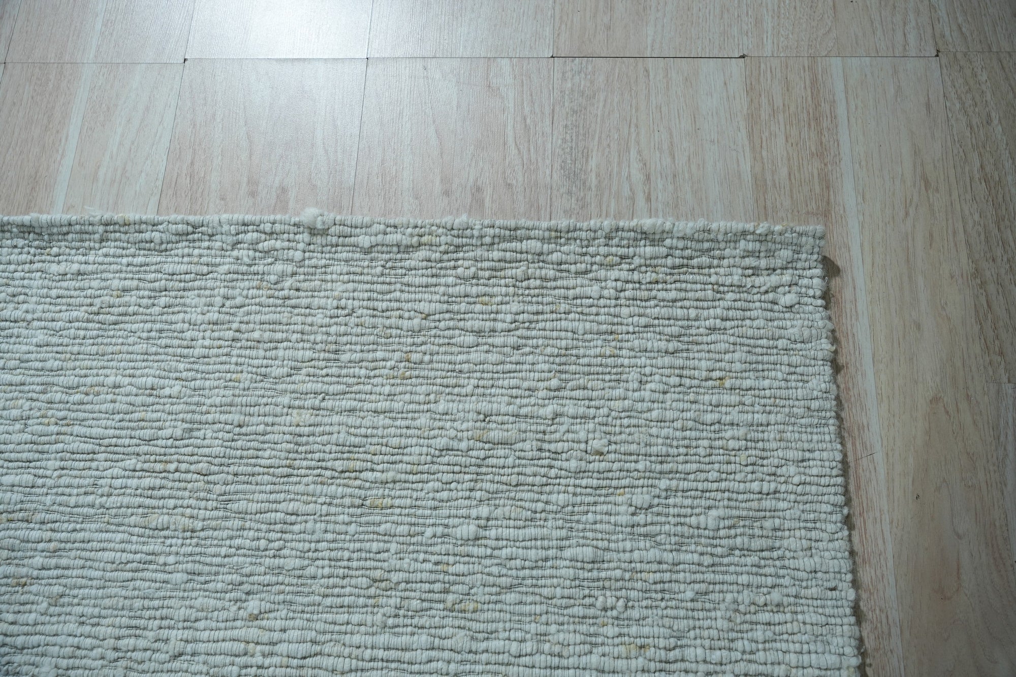 Fiona Rustic Ivory Flatweave Wool Rug, its soft ivory tones and flatweave construction complementing a bright living space with natural light and modern furniture.