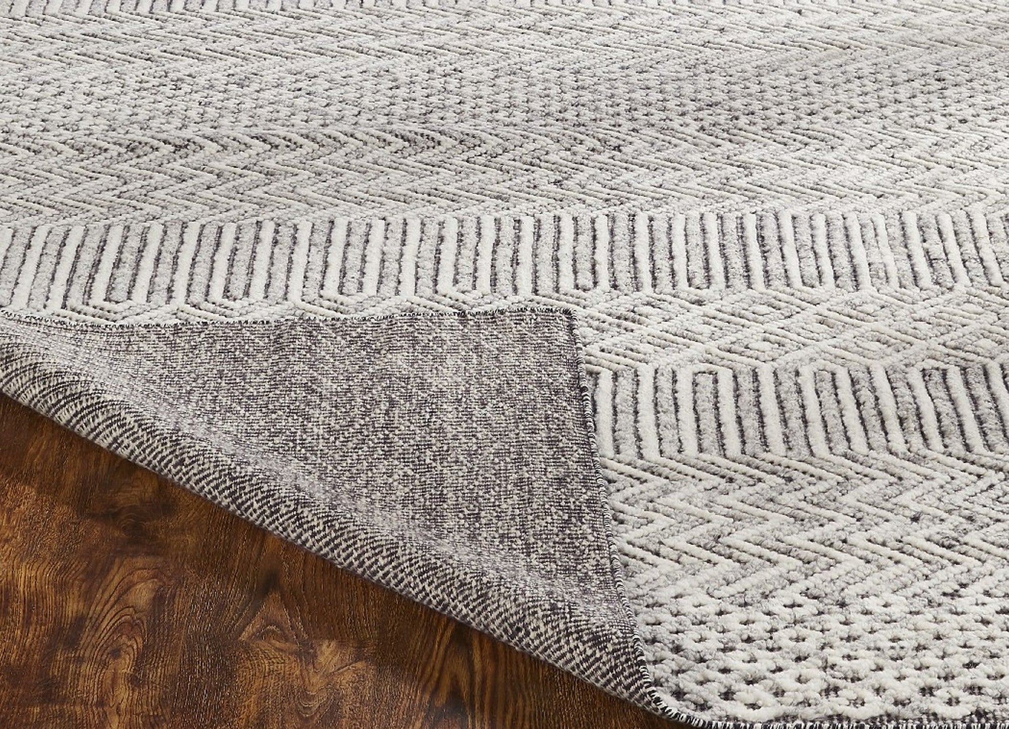 Chic Inviting Ivory Handmade Wool Rug, displaying its soft ivory hue and handcrafted texture beneath a modern living room setting, subtly contrasting with a dark hardwood floor.