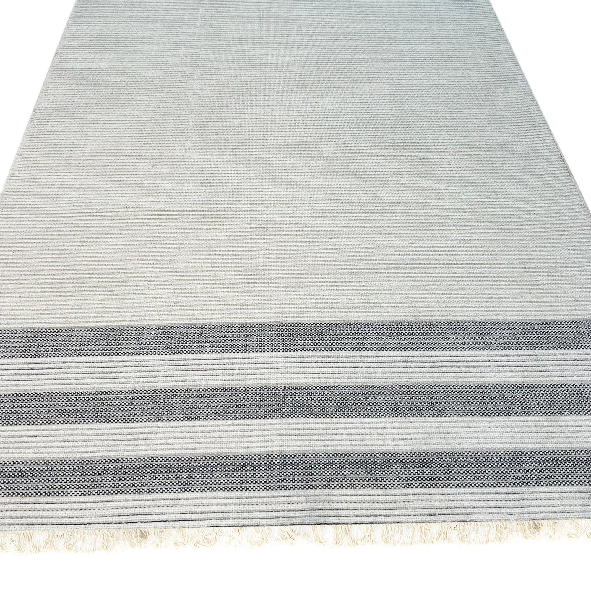 Violet Quinn White Handmade Wool Rug, showing subtle texture and a neutral color palette, sits elegantly on a light hardwood floor, creating a warm and inviting space.