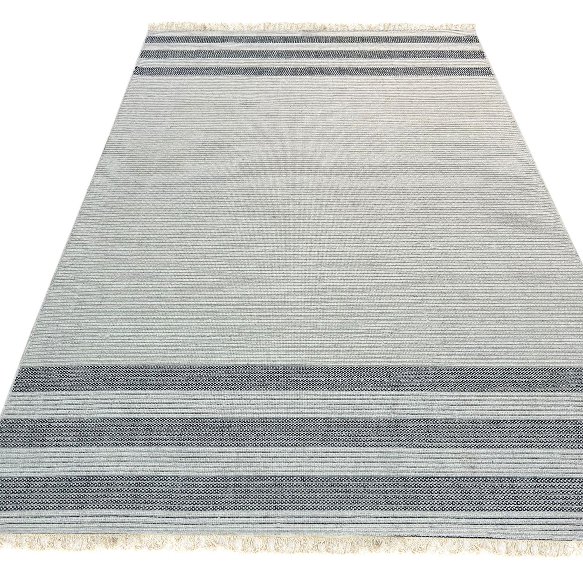 Violet Quinn White Handmade Wool Rug displayed in a bright, modern living room; its white wool texture softly contrasts with dark wooden furniture and a green plant, showcasing the rug&#39;s subtle design and plush feel.