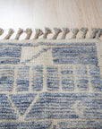 Elegant Marrakech Blue Hand-Knotted Wool Rug, showing a corner detail with vibrant blues and intricate geometric patterns, hand-knotted wool construction visible, in a room setting with hardwood flooring and natural light.