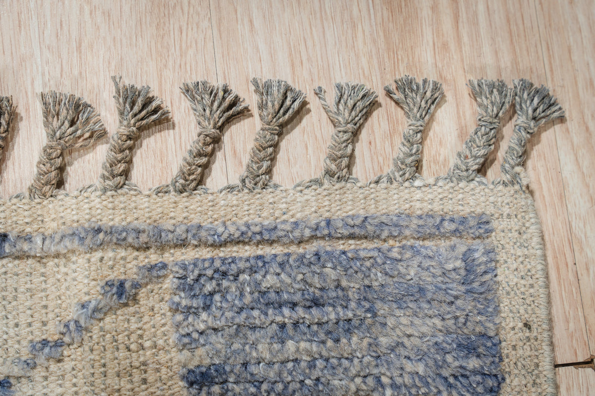 Elegant Marrakech Blue Hand-Knotted Wool Rug, a mesmerizing dance of indigo and azure hues hand-knotted in wool, graces a warmly lit living space, hinting at exotic travels and sophisticated comfort.