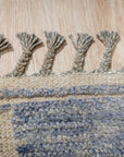 Elegant Marrakech Blue Hand-Knotted Wool Rug, a mesmerizing dance of indigo and azure hues hand-knotted in wool, graces a warmly lit living space, hinting at exotic travels and sophisticated comfort.