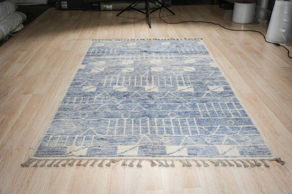 Elegant Marrakech Blue Hand-Knotted Wool Rug, showcasing its intricate geometric patterns and rich blue hues, rests on a light hardwood floor, creating a sophisticated living space.