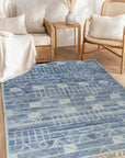 Elegant Marrakech Blue Hand-Knotted Wool Rug, its intricate geometric design in shades of blue and cream pops against a light wooden floor, showcasing the rug's texture and handmade craftsmanship.