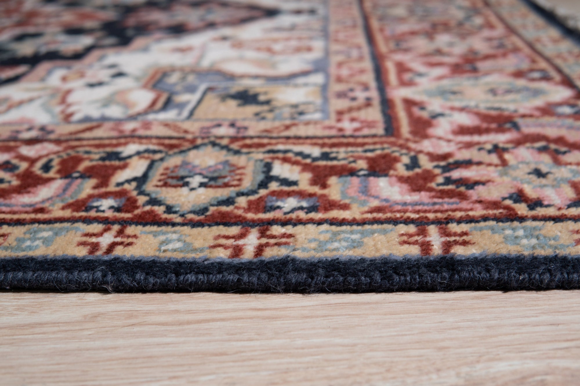 Ella Oriental Navy Hand Knotted Wool Rug, a navy and ivory wool rug with an intricate floral and geometric design, seen in a bright living room setting with a mid-century modern aesthetic.