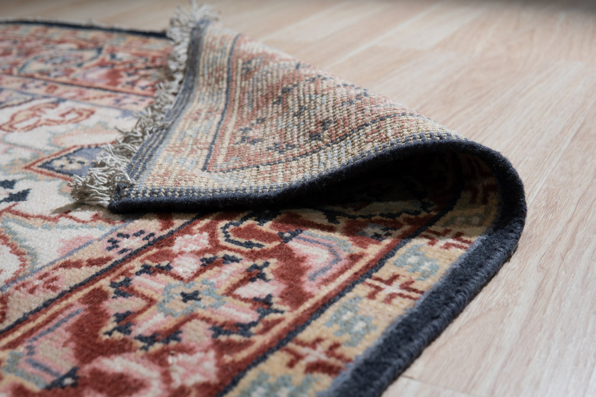 Ella Oriental Navy Hand Knotted Wool Rug, a rich navy and cream wool rug with intricate oriental motifs, lies on a hardwood floor, its hand-knotted texture adding depth and warmth to the setting.