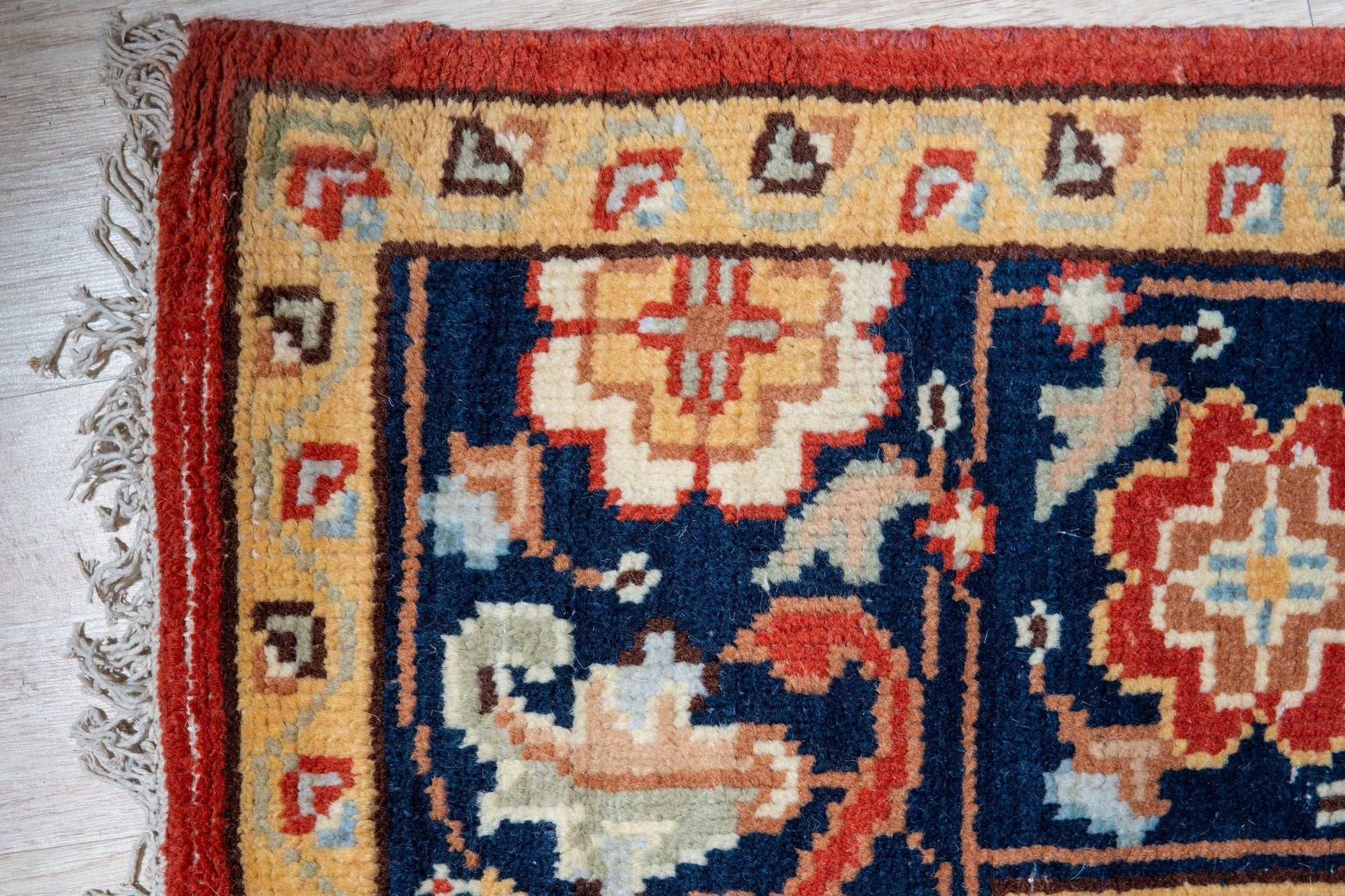 Kira Zinnia Rust Hand Knotted Wool Rug, showcasing its intricate hand-knotted construction and rich red hues, displayed in a contemporary living room setting with modern furniture.