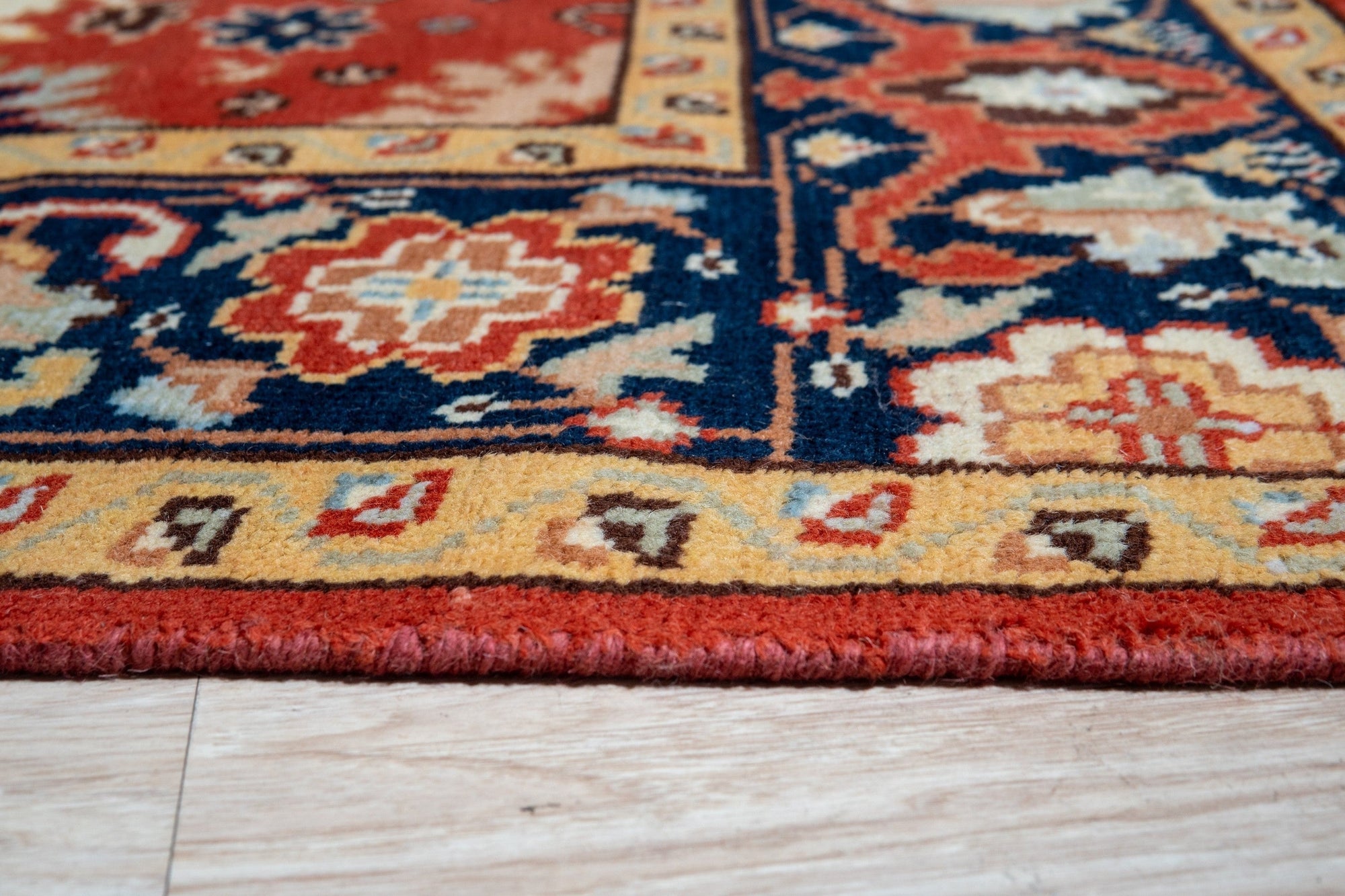 Kira Zinnia Rust Hand Knotted Wool Rug, showcasing a vibrant red hue and hand-knotted construction, displayed in a room setting to demonstrate scale and usage.